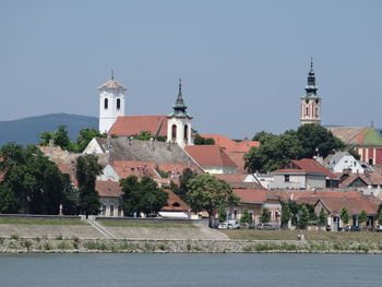 Church by buildings against clear sky