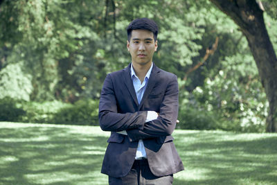 Portrait of young man standing against trees