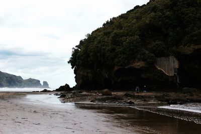 Scenic view of sea by mountain against sky