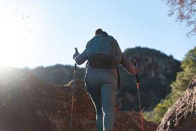 Woman climbs the mountain in the garraf natural park, supported by hiking sticks.