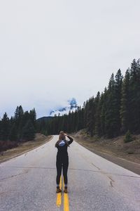 Rear view of woman standing on road against sky