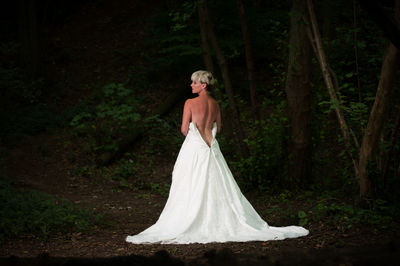 Rear view of bride wearing backless wedding dress in forest