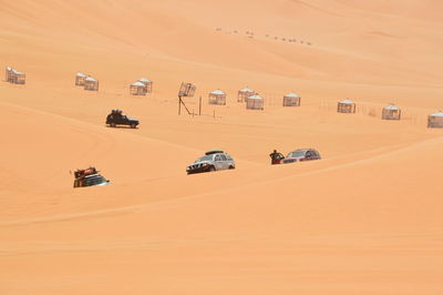 Cars on desert against sky during sunset