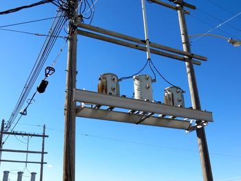 Low angle view of bird perching on electricity pylon against sky