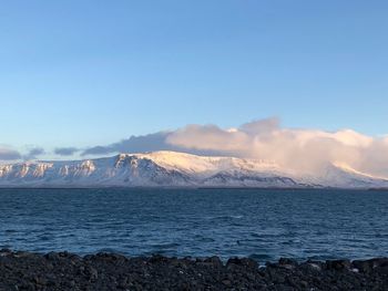 Scenic view of sea and snowcapped mountains against sky