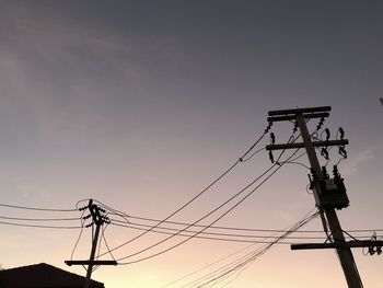 Low angle view of silhouette electricity pylon against sky during sunset