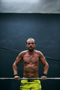 Shirtless fit young man working out in a cage at indoors gym