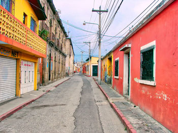 Empty road amidst buildings in city