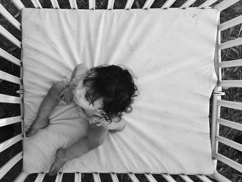 Directly above view of baby sitting in crib at back yard