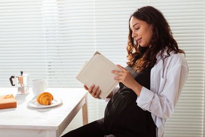 Young woman holding food while sitting on table