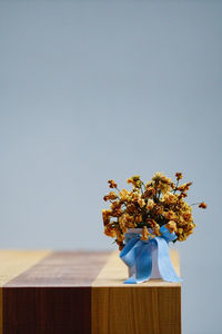 Close-up of flower vase on table against sky