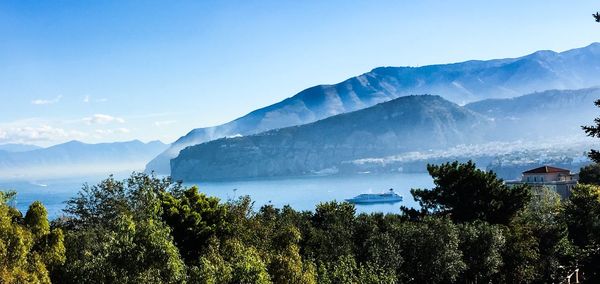 Scenic view of trees and mountains against blue sky