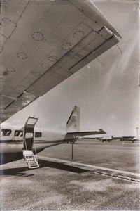 Close-up of airplane on airport runway against sky