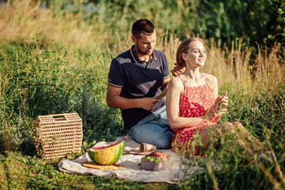 Young couple in love on summer picnic with watermelon. loving couple sitting by the river, talking