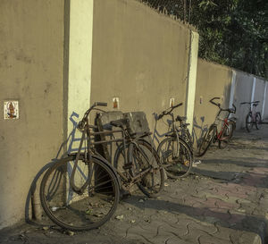 Bicycle parked on footpath against wall