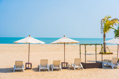 Chairs and parasols on beach against clear sky