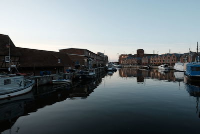 Boats moored at harbor against buildings in city