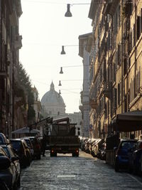 Vehicles on road against sky in city