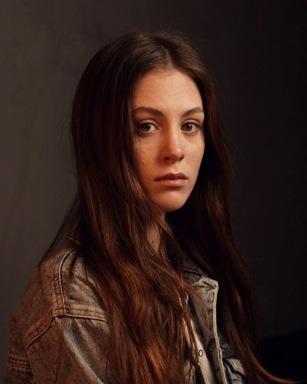 long hair, portrait, hair, looking at camera, hairstyle, one person, young adult, indoors, headshot, young women, beauty, beautiful woman, brown hair, lifestyles, front view, women, studio shot, adult, black background, contemplation