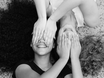 High angle view of smiling mother and daughter covering eyes while lying on floor