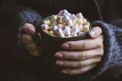 Midsection of woman carrying marshmallows in cup