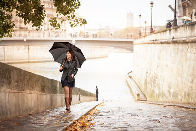 Brunette girl in a black jacket walks on the river embankment