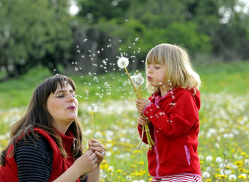 Mother and daughter playing with dandelions at park