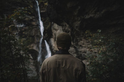 Rear view of man standing against waterfall