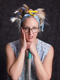 Portrait of woman wearing hair curlers against wall