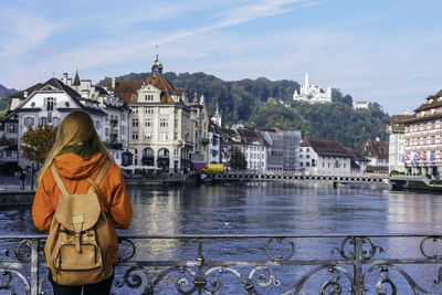 Rear view of woman standing on footbridge over river