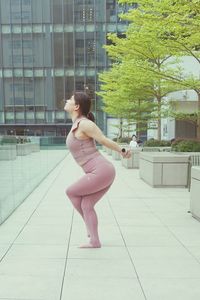 Full length of woman dancing against building in city