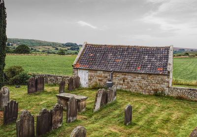 View of churchyard with building and moorland on a cloudy day.