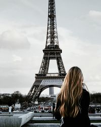 Rear view of woman standing tower against cloudy sky