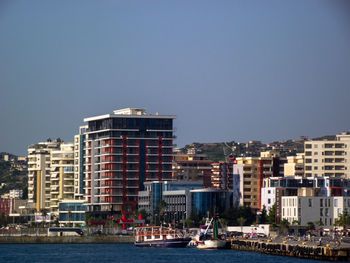 Buildings by sea against clear sky