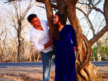 Young couple standing against tree