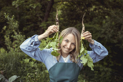 Portrait of a smiling young woman holding plants