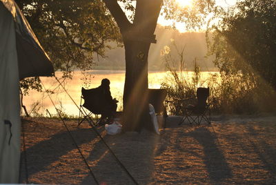 Silhouette people sitting on seat against trees