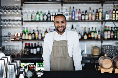 Portrait of smiling confident owner standing at checkout counter in restaurant