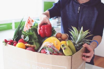 Midsection of man holding fruits in box
