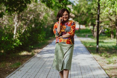 Smiling freelancer woman using smartphone outdoors in park