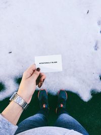 High angle view of woman holding card with text on snow covered field