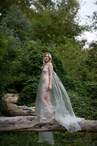 Woman standing by tree in forest