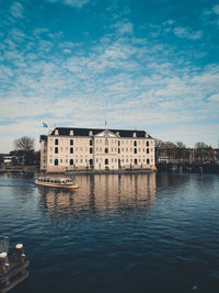 Buildings by river against sky