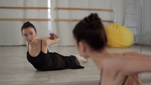 Young woman looking away while sitting on floor