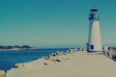 Lighthouse by sea against sky