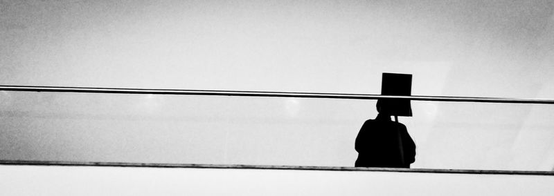 Rear view of silhouette man standing against railing
