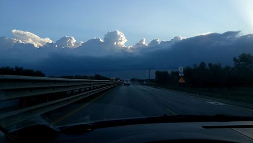 Cars on road against sky seen through car windshield