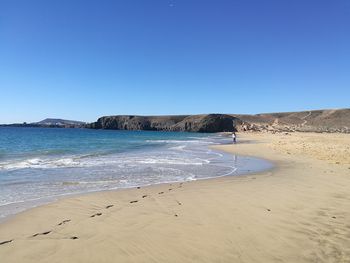 Scenic view of beach against clear blue sky