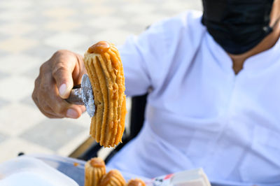 Unrecognizable seller of peruvian churros, an exquisite dessert filled with blancmange