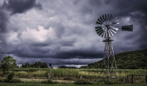 Traditional windmill on grassy field against storm clouds